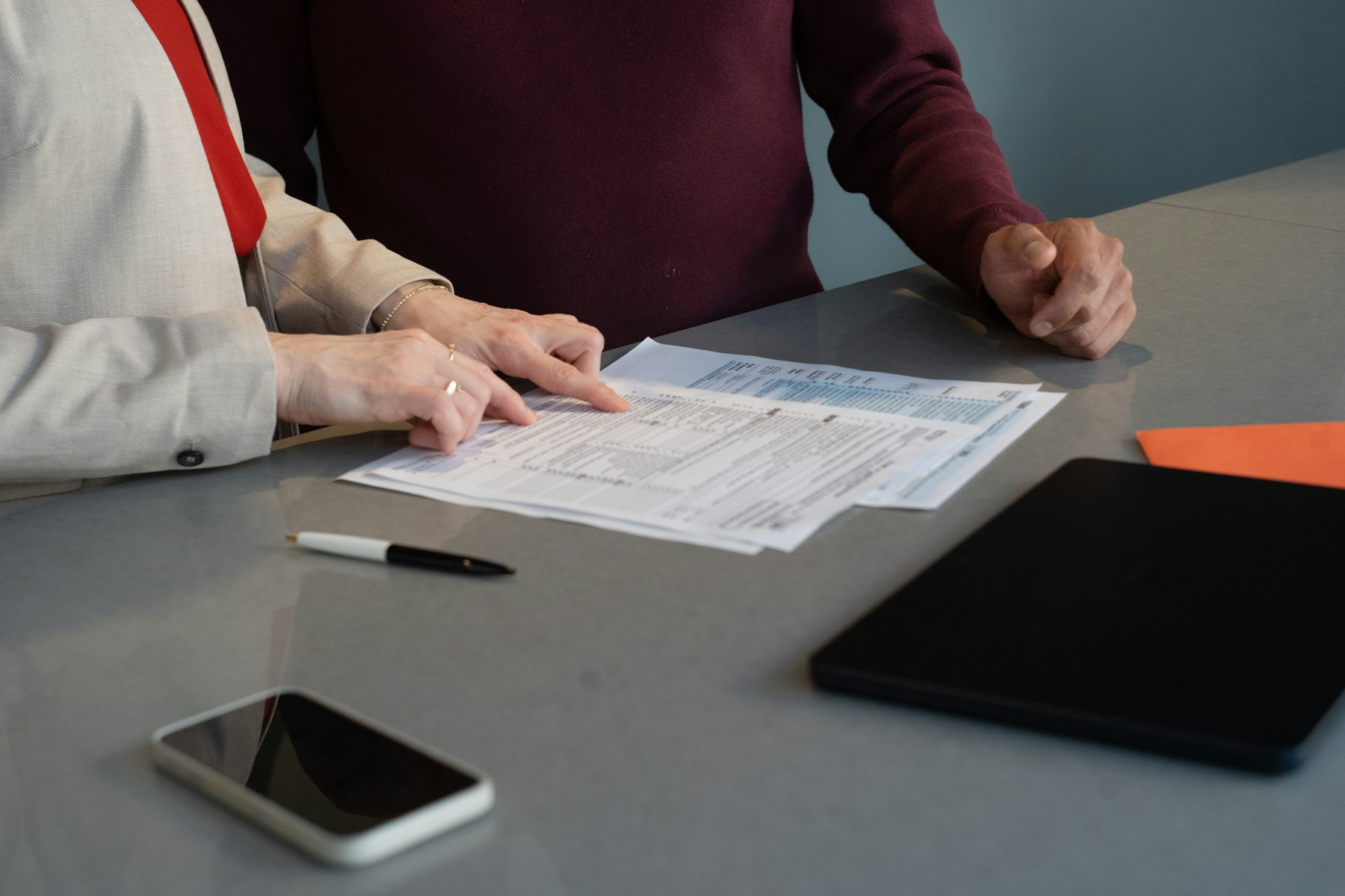 Two colleagues reviewing printed bid documents together at a table
